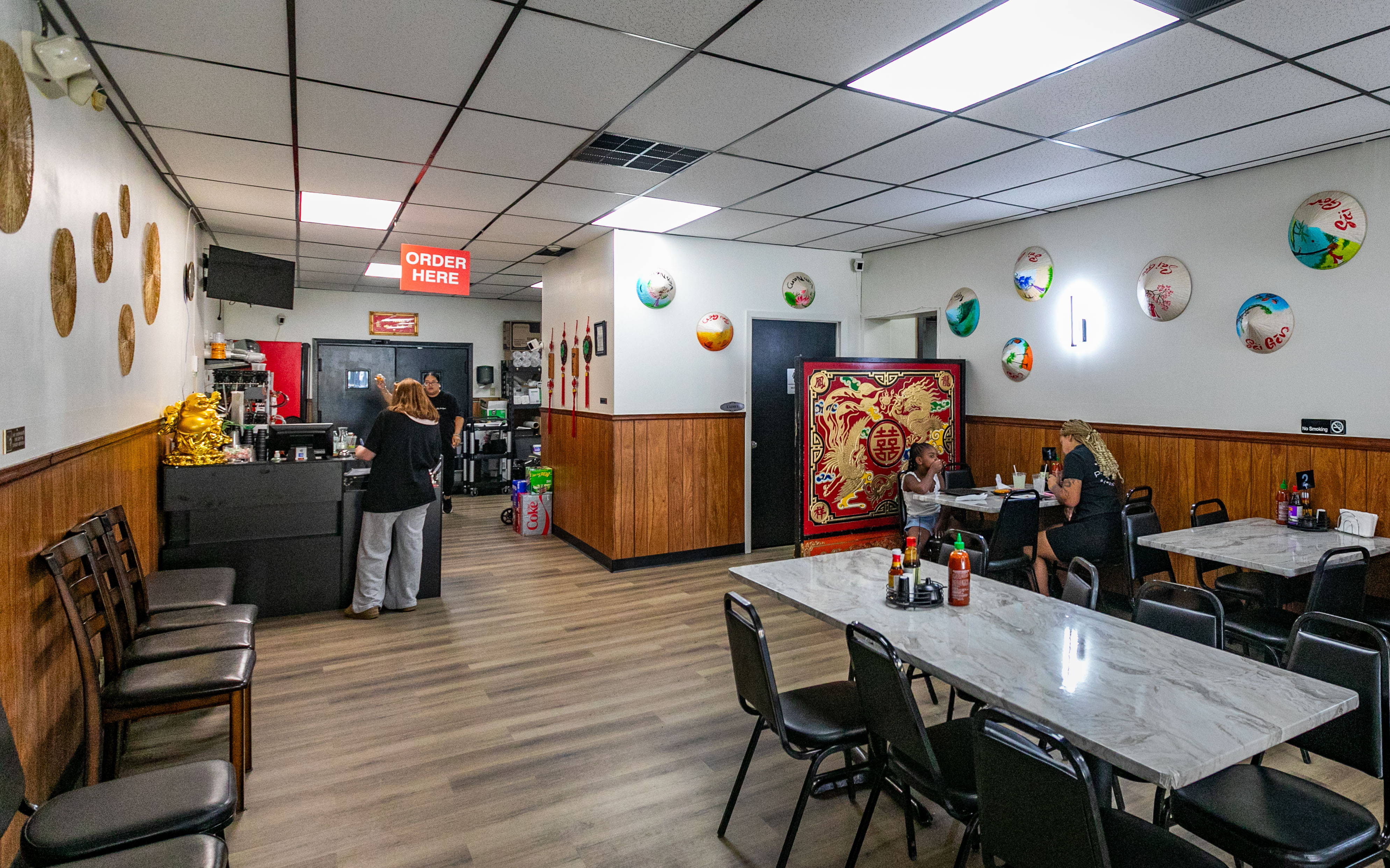The restaurant dining room with wood paneling, marble tables, painted hats and a red and gold divider